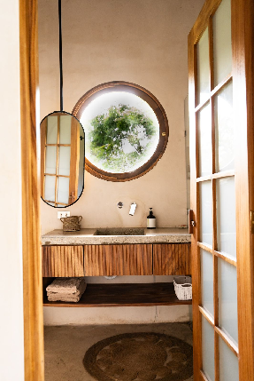 Bathroom with circular window, concrete vanity and shower with floor to ceiling tile