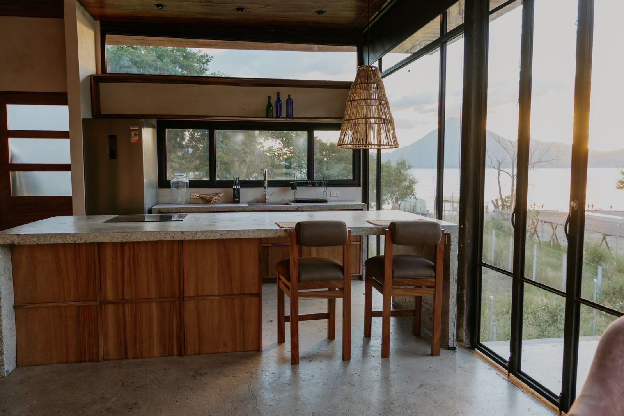 Kitchen with floor-to-ceiling steel windows, lake view, concrete island, and teak cabinetry