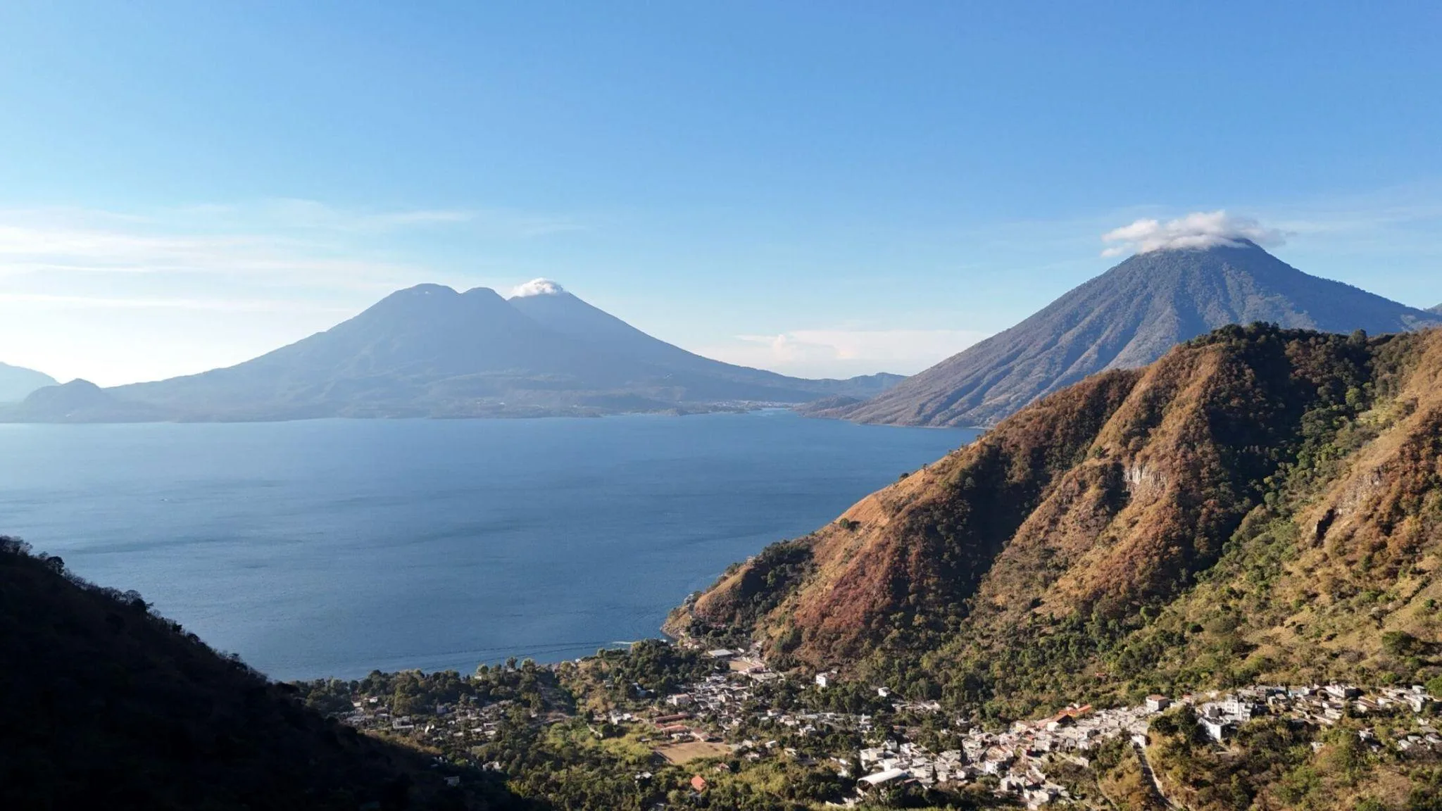 Tzununá on the north shore of Lake Atitlán, with the San Pedro, Tolimán, and Atitlán volcanoes rising across the water