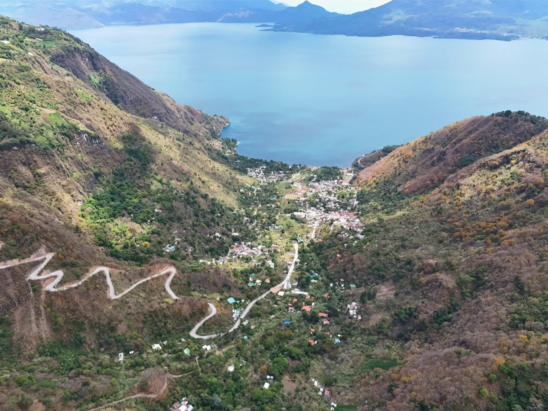 The development in the valley of Tzununá, facing south toward Lake Atitlán, with the switchback road climbing the north-shore hillside